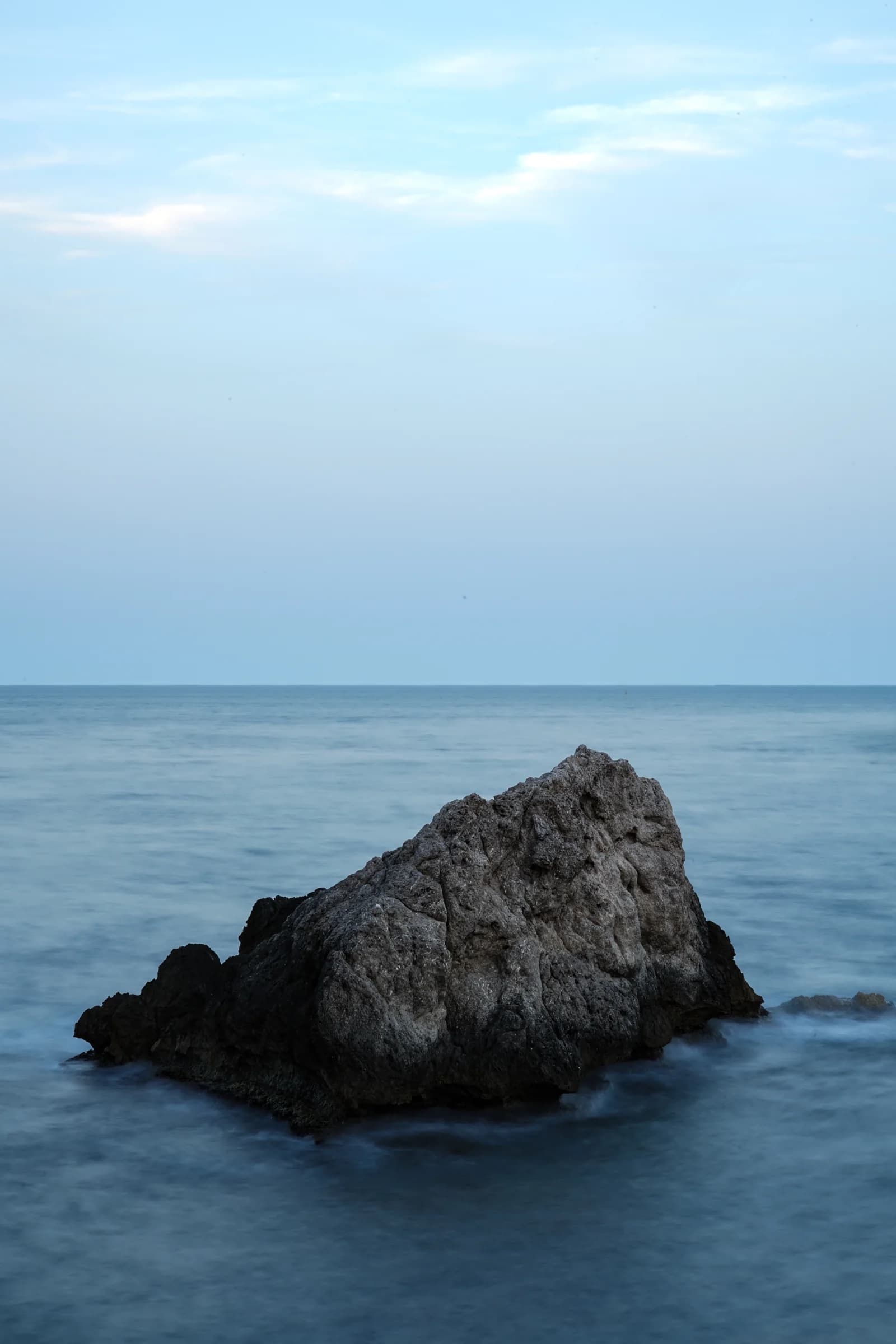 A solitary rock in a calm blue sea