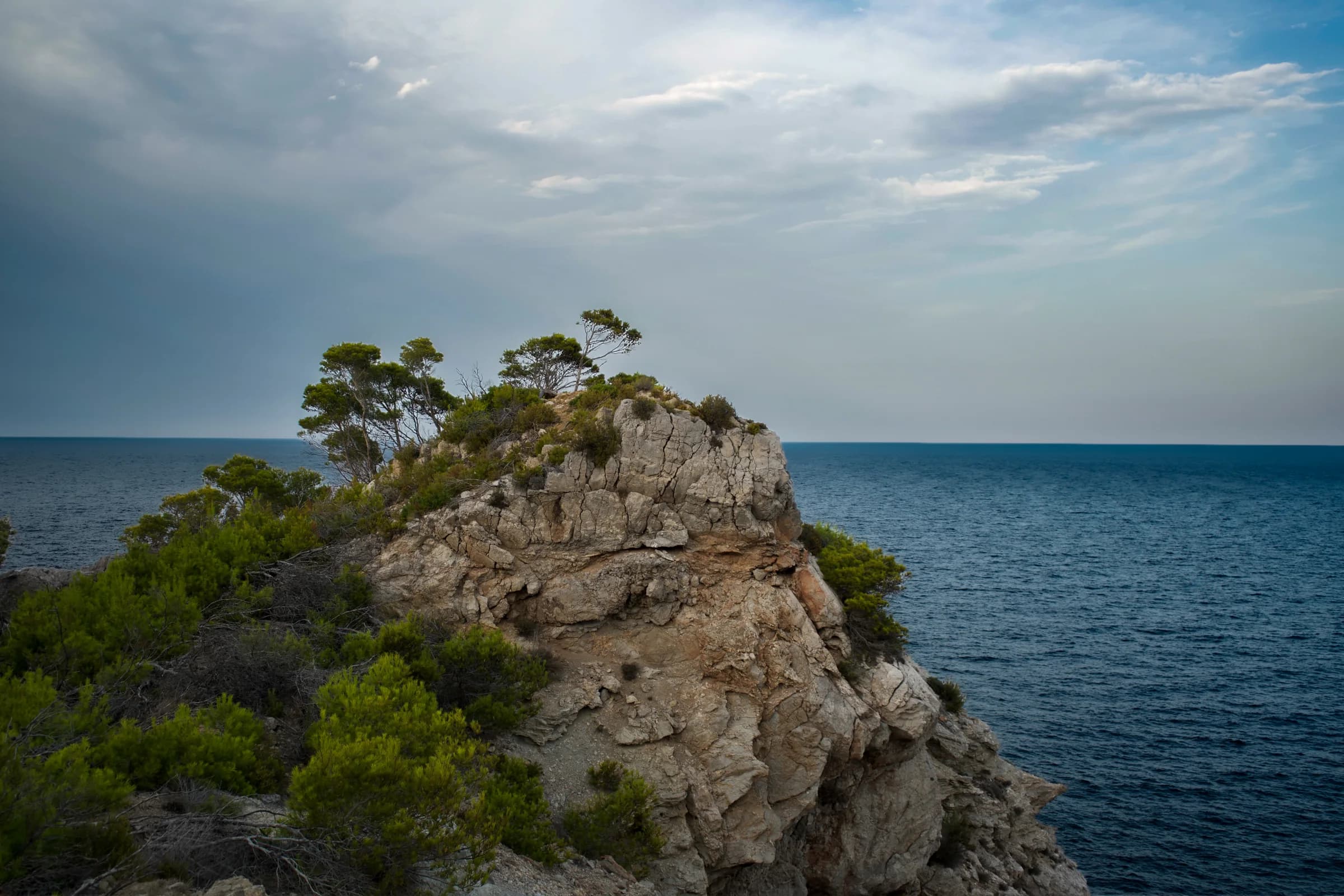 A rocky pine-covered headland opening towards the Mediterranean